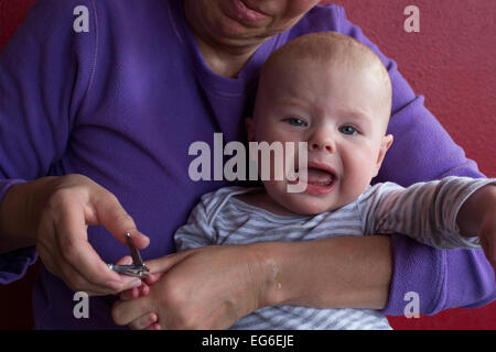 Denver, Colorado - sieben Monate alten Adam Hjermstad Jr. Schreie als seine Großmutter, Susan Newell, schneidet seine Fingernägel. Stockfoto