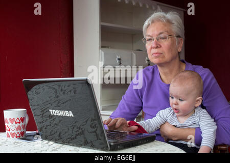 Denver, Colorado - sieben Monate alten Adam Hjermstad Jr. hilft seiner Großmutter, Susan Newell, 66, während sie an einem Computer arbeitet. Stockfoto