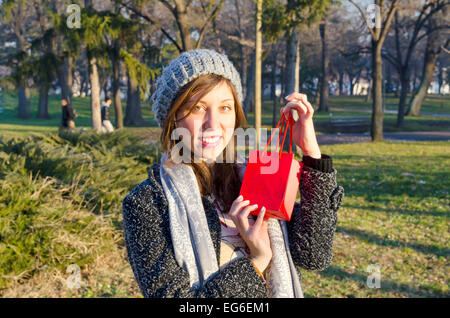 Überrascht, junges Mädchen posiert mit einer roten Geschenkbox in einem park Stockfoto