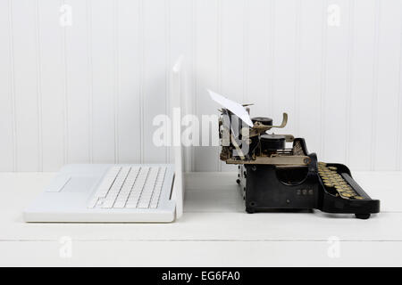 Nahaufnahme von einem weißen Schreibtisch mit einem modernen Laptop-Computer und eine antike Schreibmaschine Rücken an Rücken. Querformat mit Textfreiraum. Stockfoto