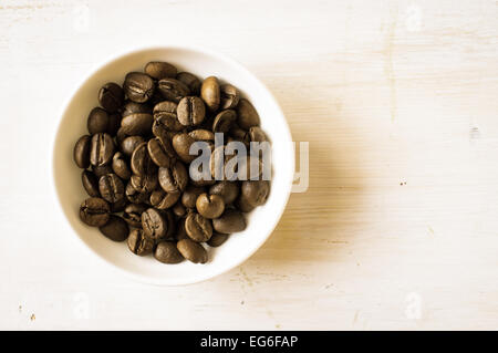 Kaffeebohnen in eine weiße Schüssel mit einer weißen Tafel Großaufnahme. Ansicht von oben Stockfoto