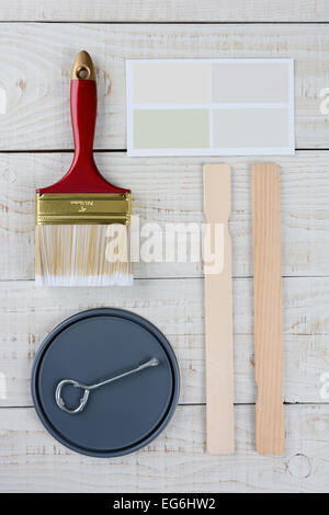 Overhead Schuss der Farbe Deckel, Opener, Farbmuster, rühren Stöcke und Farbe Pinsel auf einer rustikalen Holzoberfläche. Vertikale forma Stockfoto