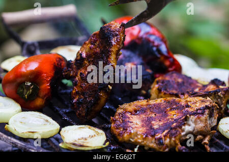 Steak, Wurst, Zwiebeln, Paprika und Toast auf einem Grill Stockfoto