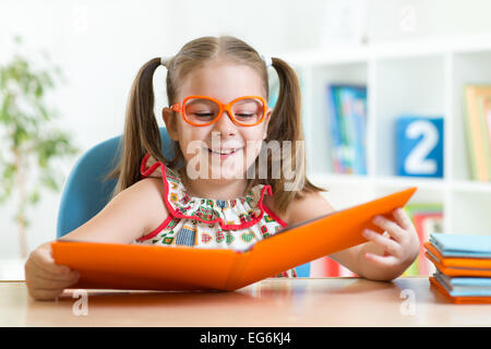 Glückliches Kind lustig Mädchen in Gläsern ein Buch zu lesen