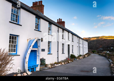 Eine Reihe von weißen terrassenförmig angelegten Bungalows mit einem alten Boot Platz an Boscastle in Cornwall Stockfoto