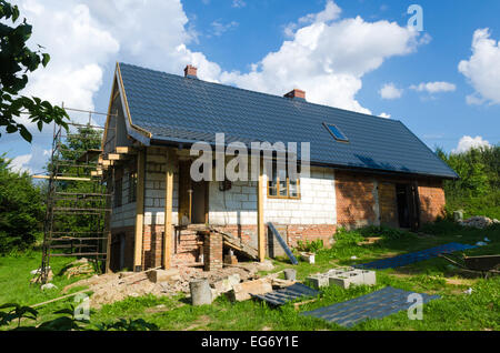 Ein Haus auf dem Lande wird renoviert und umgeben von Gerüste und Baumaterialien Stockfoto