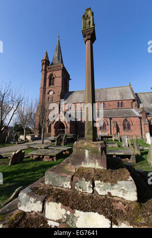 Dorf Aldford, England. Malerische Aussicht eines Denkmals Kreuz auf dem Gelände des St. Johannes der Täufer Kirche. Stockfoto