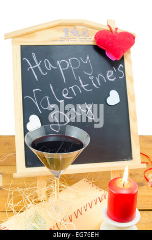 Tafel mit den Worten Happy Valentines geschrieben, verziert mit Herzen, eine Kerze und ein Glas Wein Stockfoto