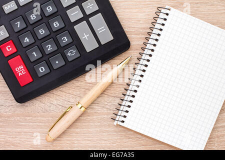 Notizbuch, Kugelschreiber und Taschenrechner auf Schreibtisch aus Holz Stockfoto