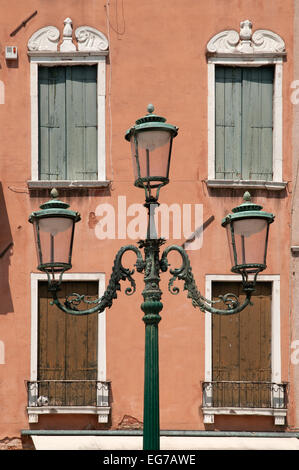 Eleganten gusseisernen Lampengestell mit drei Lampen mit Fensterläden hinter in Campo San Stefano Venedig Italien Stockfoto