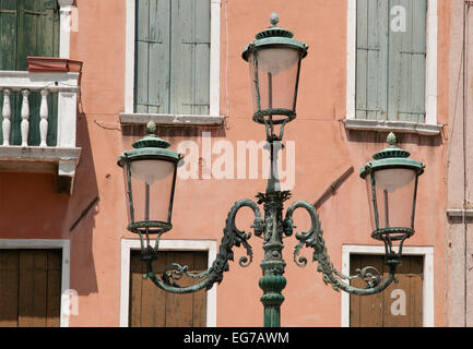 Eleganten gusseisernen Lampengestell mit drei Lampen mit Fensterläden hinter in Campo San Stefano Venedig Italien Stockfoto