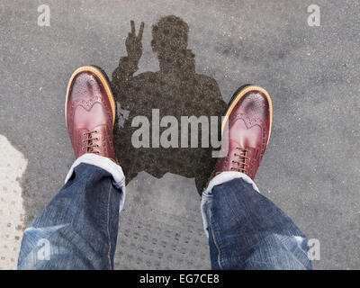 ein Selfie Reflexion Foto in einer Pfütze macht ein zwei Finger-Peace-Zeichen Stockfoto