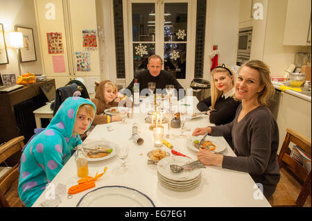 Eine Familie genießen Sie eine Mahlzeit in der Küche mit den Kindern in Onesies gekleidet Stockfoto