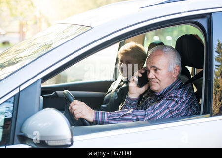 ältere Fahrer im Auto mit Smartphone, Beifahrerin im Auto zu sitzen Stockfoto