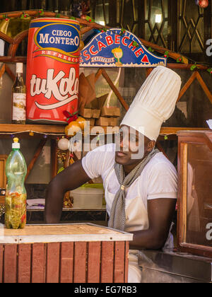 Ein Afro-kubanischen Restaurant Arbeiter in einer hohen weißen Kochmütze nimmt sich eine Auszeit in Havanna, Kuba. Stockfoto