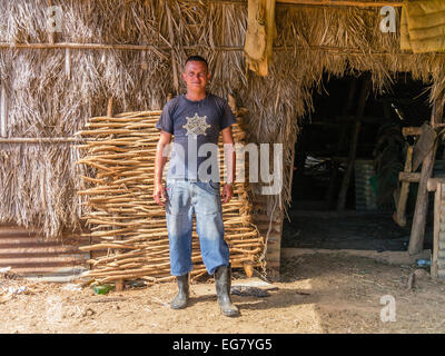 Ein junge kubanische männlichen Tabak Landarbeiter steht vor einer Tabak trocknen Schuppen gebildet von getrockneten Palmwedeln in Viñales, Kuba. Stockfoto