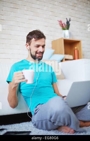 Hübscher Kerl in Freizeitkleidung mit moderne Geräte zu Hause Stockfoto