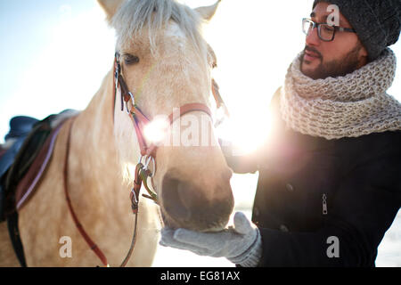 Junger Mann im Winterwear und sein Pferd Stockfoto
