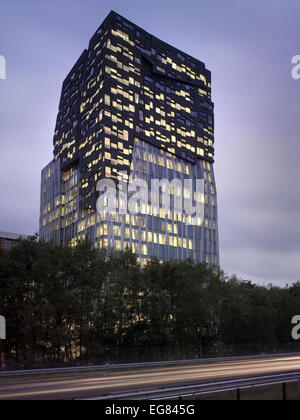 Der Felsen, Amsterdam, Niederlande. Architekt: Erick van Egeraat, 2011. Beleuchtete Gebäude in der Dämmerung. Stockfoto