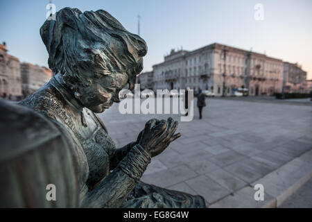 Triest, Italien - die Statue "Sartine" leuchtet von den letzten Strahlen der Sonne während hinter Menschen zu Fuß auf der Piazza Unità d ' Italia Stockfoto