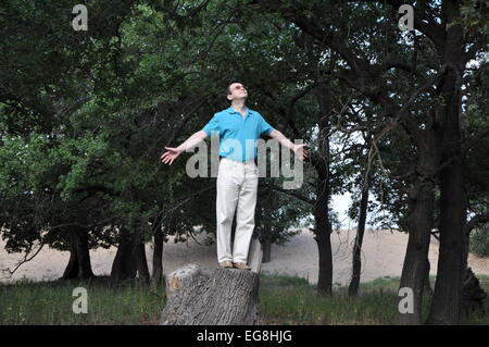 Glücklicher Mann stehend auf einem hohen Baumstumpf in dem Eichenwald Stockfoto