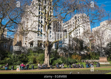 Menschen sitzen und entspannen im Winter Sonne, Victoria Embankment Gardens, London, UK Stockfoto