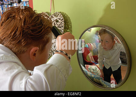 Junge, seine Haare zu kämmen, vor der Abreise für die Schule Stockfoto