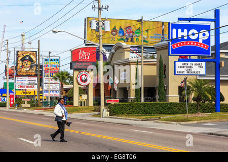 Frau, die Überquerung der International Drive, Orlando, Florida, vor Werbetafeln, Amerika Stockfoto