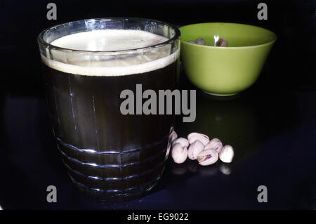 Dunkles Bier und Pistazien auf schwarzem Hintergrund Stockfoto