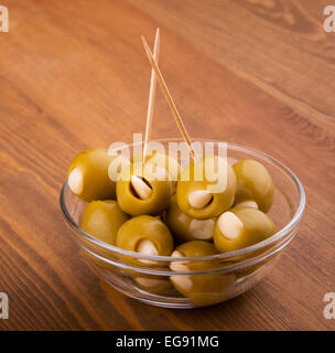 Grüner Knoblauch gefüllte Oliven in eine Glasschüssel auf dunklen Holztisch Stockfoto