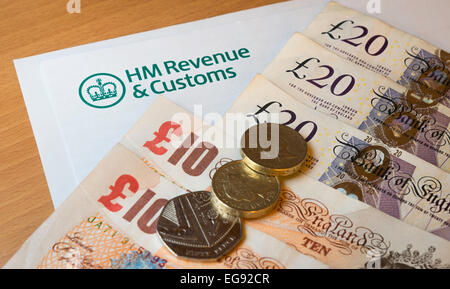 HMRC (Her Majesty es Einnahmen und Zoll) Briefkopf auf einem Tisch, umgeben von Geld - Pfund Sterling. Stockfoto