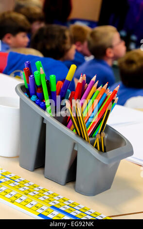 Kunststoff Behälter mit Kugelschreiber und Bleistifte in einem Klassenzimmer der Grundschule mit Schülerinnen und Schülern im Hintergrund Stockfoto