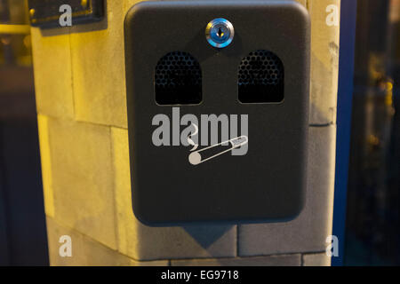 Aschenbecher, die aussieht wie ein Gesicht an der Wand außerhalb. London, UK. Seit das Rauchverbot an öffentlichen Plätzen sind diese Aschenbecher ein alltäglicher Anblick geworden, wie Raucher zum Rauchen gehen. Stockfoto