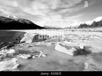 Klumpen Eis und Schnee am Strand des Chilkat Inlet im Winter in schwarz und weiß. Stockfoto