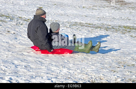 Mann und der junge auf Schlitten zusammen Rodeln bergab auf verschneiten Hügel Caldbeck Fells, Lake District, Cumbria, England UK Stockfoto