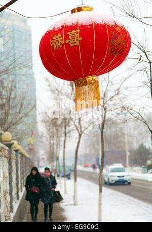 Chengde, Chinas Provinz Hebei. 20. Februar 2015. Anwohner laufen vorbei an einem verschneiten rote Laterne auf einer Straße in Pingquan County von Chengde, Nordchinas Provinz Hebei, 20. Februar 2015. Regen und Schnee hat Ost- und Zentral-China seit Donnerstag, dem zweiten Tag des Lunar New Year Ferien getroffen. Bildnachweis: Liu Huanyu/Xinhua/Alamy Live-Nachrichten Stockfoto