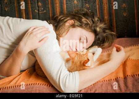 Junge Frau, die zusammen mit Ingwer Katze schläft Stockfoto