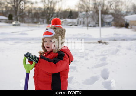 Junge stand im Schnee mit Schaufel Stockfoto