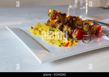 Curry-Hähnchen-Spieße mit Reis auf weißen Teller Stockfoto