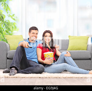 Junges Paar vor dem Fernseher sitzen auf dem Boden zu Hause Schuss mit einem Tilt-Shift-Objektiv Stockfoto
