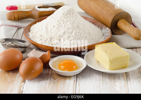Backzutaten - Eiern, Mehl, Zucker, butter auf Holztisch Stockfoto