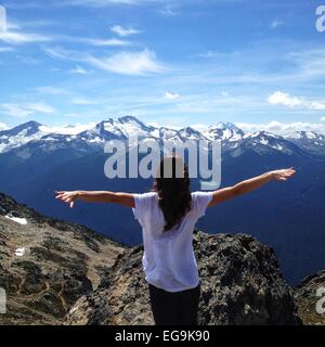 Frau auf dem Berg stehend mit ausgestreckten Armen, Whistler, British Columbia, Kanada Stockfoto