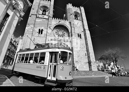 Portugal, Lissabon: Historische Straßenbahn mit Touristen vorbei an der mittelalterlichen Kathedrale in der Alfama als schwarz-weiß-version Stockfoto