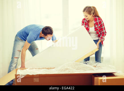 lächelnde paar Eröffnung großer Karton mit sofa Stockfoto