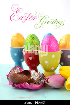 Glücklich Schokolade Ostereier in helle Farbe Folie in rot, gelb, blau, grün und lila Tupfen Eierbecher, vertikale Witz verpackt Stockfoto