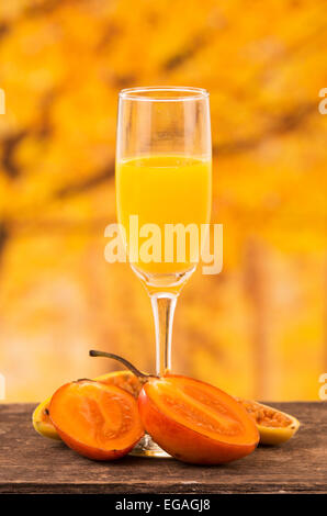 Glas Saft mit Baum Tomaten und Bananen-Passionsfrucht-Scheiben auf einem Holztisch Stockfoto