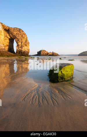 Perranporth Strand bei Sonnenaufgang an einem klaren Morgen zeigen, einen großen Bogen in der Landzunge, die den Sand im Wasser reflektieren. Stockfoto