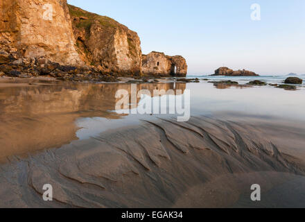 Perranporth des beeindruckende natürlichen Bogen reflektiert auf dem sandigen Strand an einem klaren Morgen. Es gibt Muster in den Sand. Stockfoto