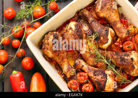 Gebratene Hähnchen-Drumsticks mit Gemüse in einer Pfanne auf einem hölzernen Hintergrund Stockfoto