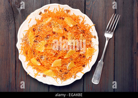 Weihnachten-Salat aus Möhren mit Orangen, Rosinen und gerösteten Sesamsamen auf einem hölzernen Hintergrund Stockfoto